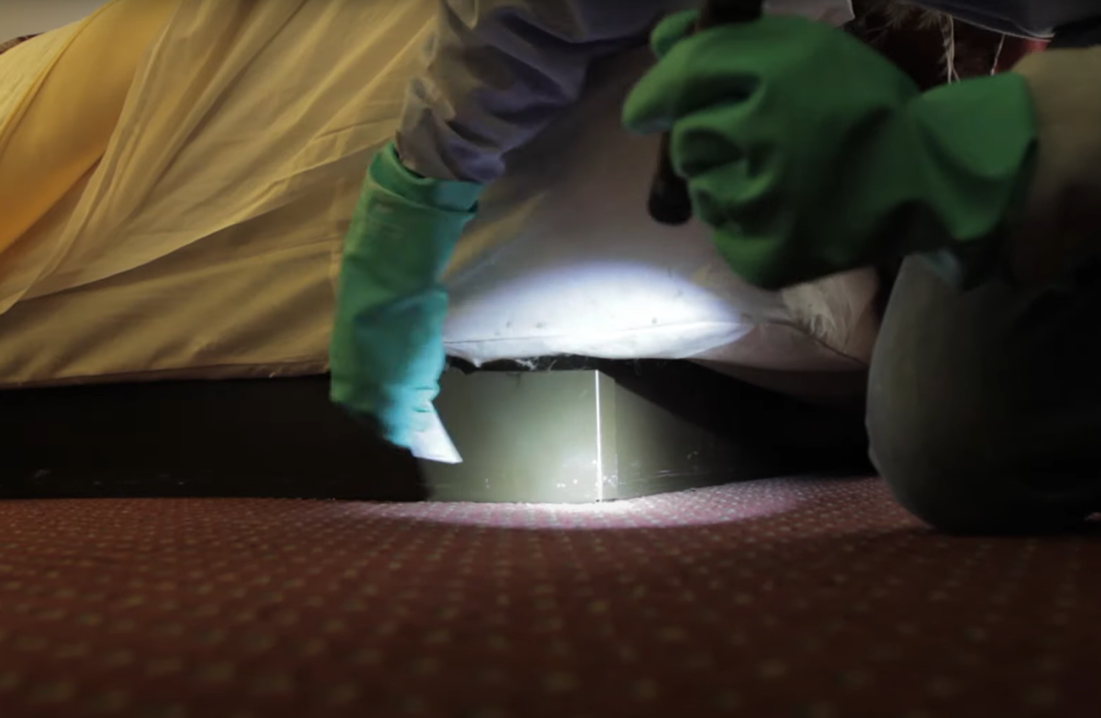 Pest control service in Brookline inspecting under a bed with professional extermination equipment